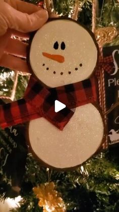 a snowman ornament hanging from a christmas tree in front of a sign