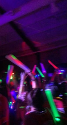 a group of people are dancing at a party with colorful lights on the dance floor