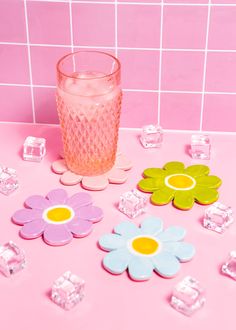 there are flowers and ice cubes on the counter next to each other in front of a pink tiled wall