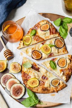 sliced figs and cheese pizza on a wooden platter with honey in the background