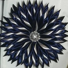 a blue and silver flower brooch sitting on top of a white jacket