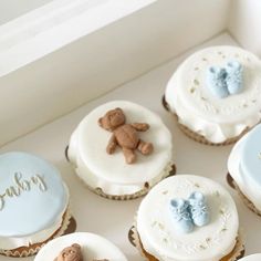 there are many cupcakes in the box with teddy bears on them and one is blue