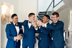 three men in blue suits are toasting each other