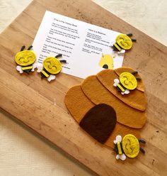 a wooden cutting board topped with paper cut out of bees and a piece of paper on top of it