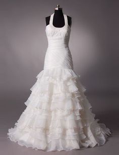 a white wedding dress on display in front of a gray background