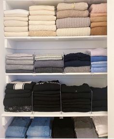 an organized closet with folded towels, sweaters and pants on shelving unit shelves