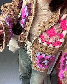 a woman is wearing a crocheted jacket with flowers on it