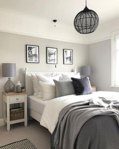 a white bed sitting in a bedroom next to two pictures on the wall and a lamp