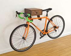 an orange bike leaning against a wall with a wooden box on it's back