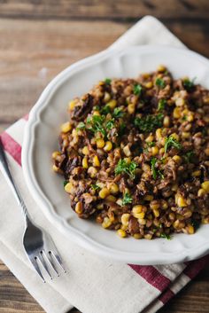 a white bowl filled with food on top of a wooden table next to a fork