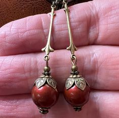 Simple vintage inspired earrings with 10mm Swarovski Bordeaux/Wine colored Crystal Pearls. The earrings are accented with antiqued brass bead caps. They are approximately 2.5 inches long and come in a gift box. Red Clip-on Earrings As Gift, Red Victorian Earrings As Gift, Victorian Red Earrings As Gift, Vintage Metal Earrings With Round Beads, Vintage Metal Beaded Earrings, Vintage Bronze Earrings With Round Beads, Vintage Bronze Round Bead Earrings, Red Brass Drop Earrings, Red Brass Earrings With Ear Wire