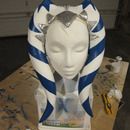 a white mannequin head with blue and silver stripes on it's face