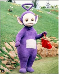 a person in a purple costume holding a red bag and standing on a grassy hill