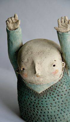 a ceramic figurine that is upside down on its head and hands in the air