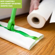 a person with a green brush on top of a piece of paper next to a roll of tape