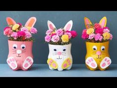 three vases with flowers in them are decorated like rabbits and cats, one is painted yellow, the other pink