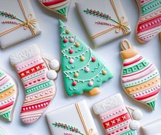 decorated christmas cookies on a white surface with ornaments and baubles in the background