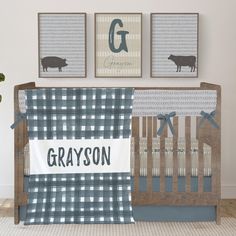 a baby crib with two pictures on the wall above it and a gray plaid blanket