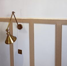 a wall mounted light on the side of a white wall next to a wooden door