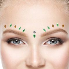 a woman's face with green leaves on her forehead and eyebrows, as well as makeup