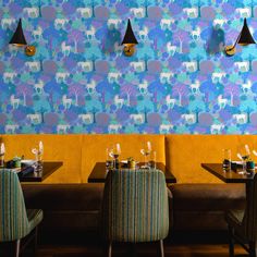 a restaurant with blue and yellow wallpaper on the walls, two chairs at tables in front of them