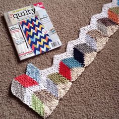 a magazine laying on the floor next to a crocheted piece of clothing and a knitted tie