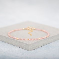 Subtle coral pink Rhodochrosite gemstones are teamed with gold for beachy tones in this very delicate and dainty bracelet. Although tiny, just 2mm, these natural Rhodochrosite beads are highly polished and micro faceted for ultimate sparkle and shine, and are interspersed with even tinier 1.3mm Gold Vermeil beads. Rhodochrosite gets is name from the Greek word 'Rhodon', meaning Rose Colour. It is considered by some to be a stone of love, and is associated with the Heart Chakra.  This slim bracel Dainty Pink Bracelet With Natural Stones, Dainty Pink Natural Stone Bracelet, Dainty Pink Bracelets With Gemstone Beads, Dainty Pink Gemstone Bead Bracelets, Dainty Pink Gemstone Beads Bracelet, Dainty Pink Beaded Bracelets With Gemstone Beads, Pink Opal Bracelets As Gifts, Peach Round Beads Bracelet As Gift, Dainty Pink Bracelets With Faceted Beads