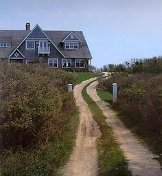 a large house sitting on top of a lush green hillside next to a dirt road