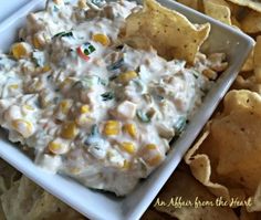 a white plate topped with chips next to a bowl of dip