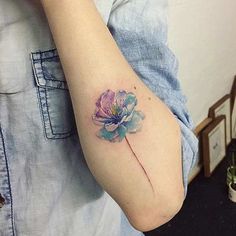 a woman's arm with a flower tattoo on the left side of her arm