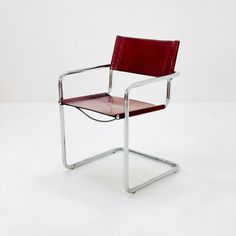 a red leather chair sitting on top of a white floor next to a metal frame