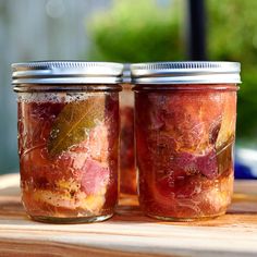 two jars filled with food sitting on top of a wooden table