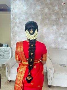 a woman with long black hair in a red sari and gold jewelry on her head