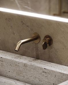 a close up of a faucet on a sink with marble counter top and gold fixtures