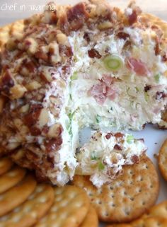 a cheese ball with crackers and grapes on it sitting next to some crackers