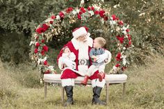 a santa clause sitting on a bench with his two babies in front of an archway