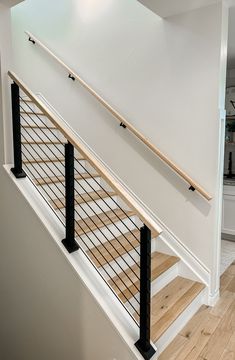 a white staircase with black railing and wooden handrails