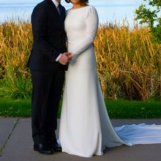 a man and woman standing next to each other in front of a field with tall grass