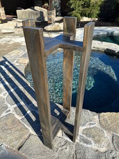 a tall wooden stand sitting on top of a stone patio next to a swimming pool