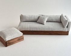 a couch and footstool sitting next to each other on a white floor in front of a wall