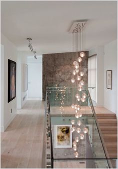 an elegant staircase with glass railing and chandelier hanging from it's ceiling