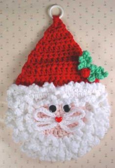 a crocheted santa clause ornament hanging on a wall with a red hat