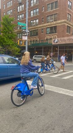 a woman riding a blue bike across a street