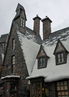 an old building with snow on the roof and two large chimneys in front of it