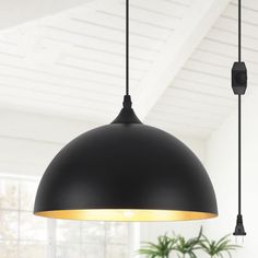 a black lamp hanging from a ceiling in a room with white walls and flooring