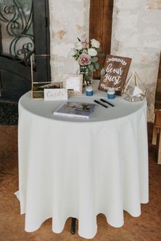 a table with a sign and flowers on it in front of a fireplace at a wedding