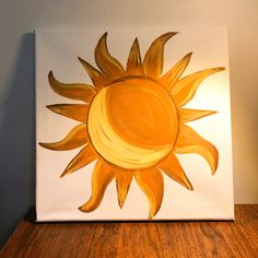 an acrylic painting of a yellow sun on a white canvas with wood flooring