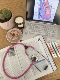 an open book with a stethoscope on top of it next to a laptop