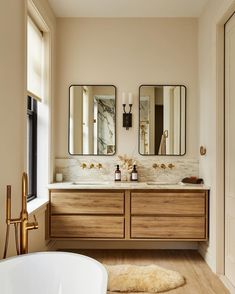 a bathroom with two sinks, mirrors and a bathtub in the middle of it