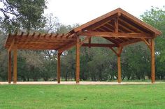 a wooden gazebo sitting on top of a lush green field